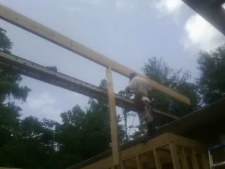Carpenter setting a ridge beam over a new addition frame — Ice Dam Removal by Roofing Brothers in What Cheer