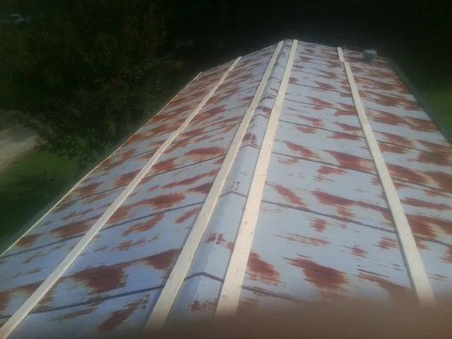 Rusted metal roof panels with new wood purlins before replacement — Storm Damage Roof Repair in What Cheer by Roofing Brothers