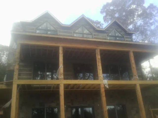 Dormers and porch framing on a large log home under construction — Roof Coating work by our crew in What Cheer