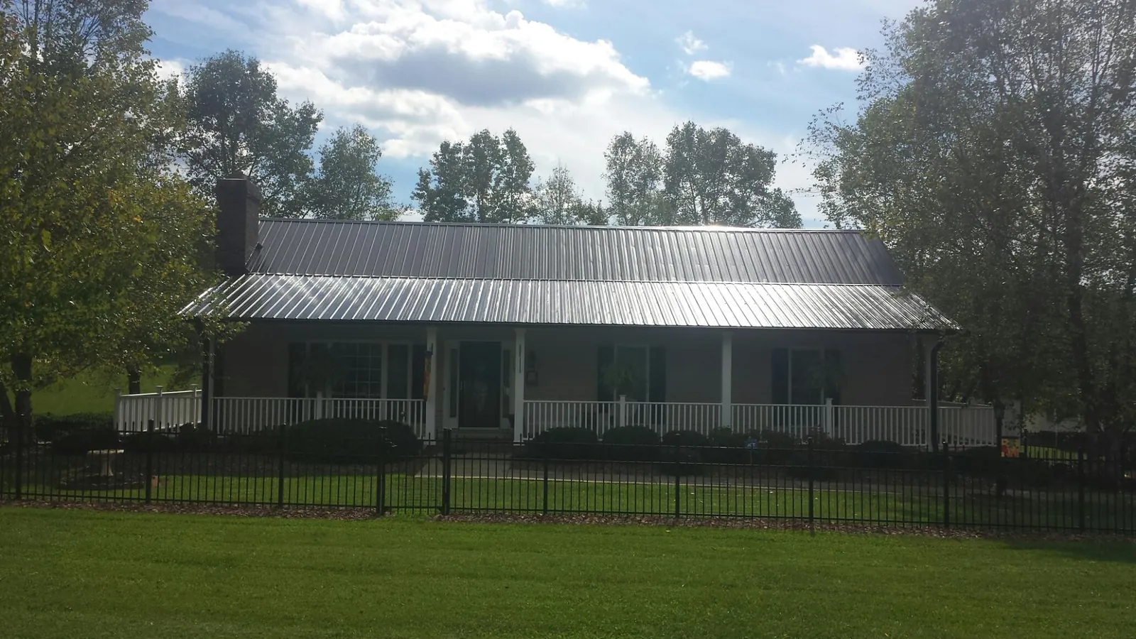 Gray metal roof on a brick ranch with a full width front porch — Gutter Guard Installation work by our crew in What Cheer