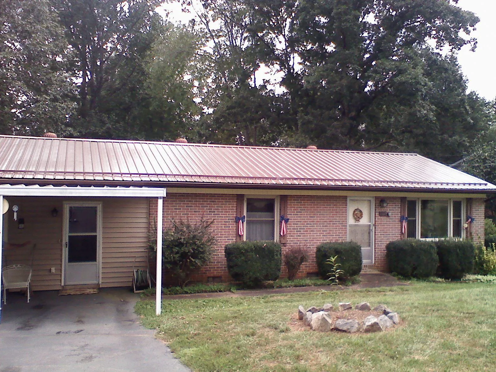 Bronze metal roof and carport on a brick ranch home — Roof Repair work by our crew in What Cheer