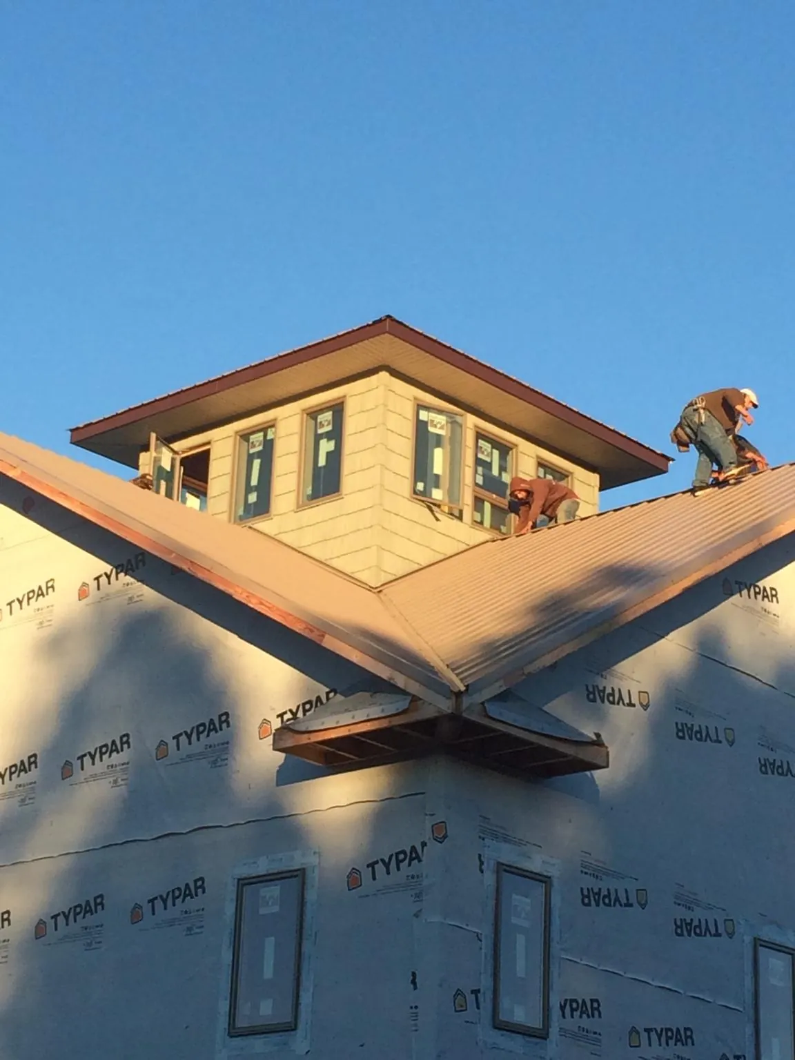 Roofers working around a rooftop cupola on a new metal roof at sunset — Roof Waterproofing in What Cheer by Roofing Brothers